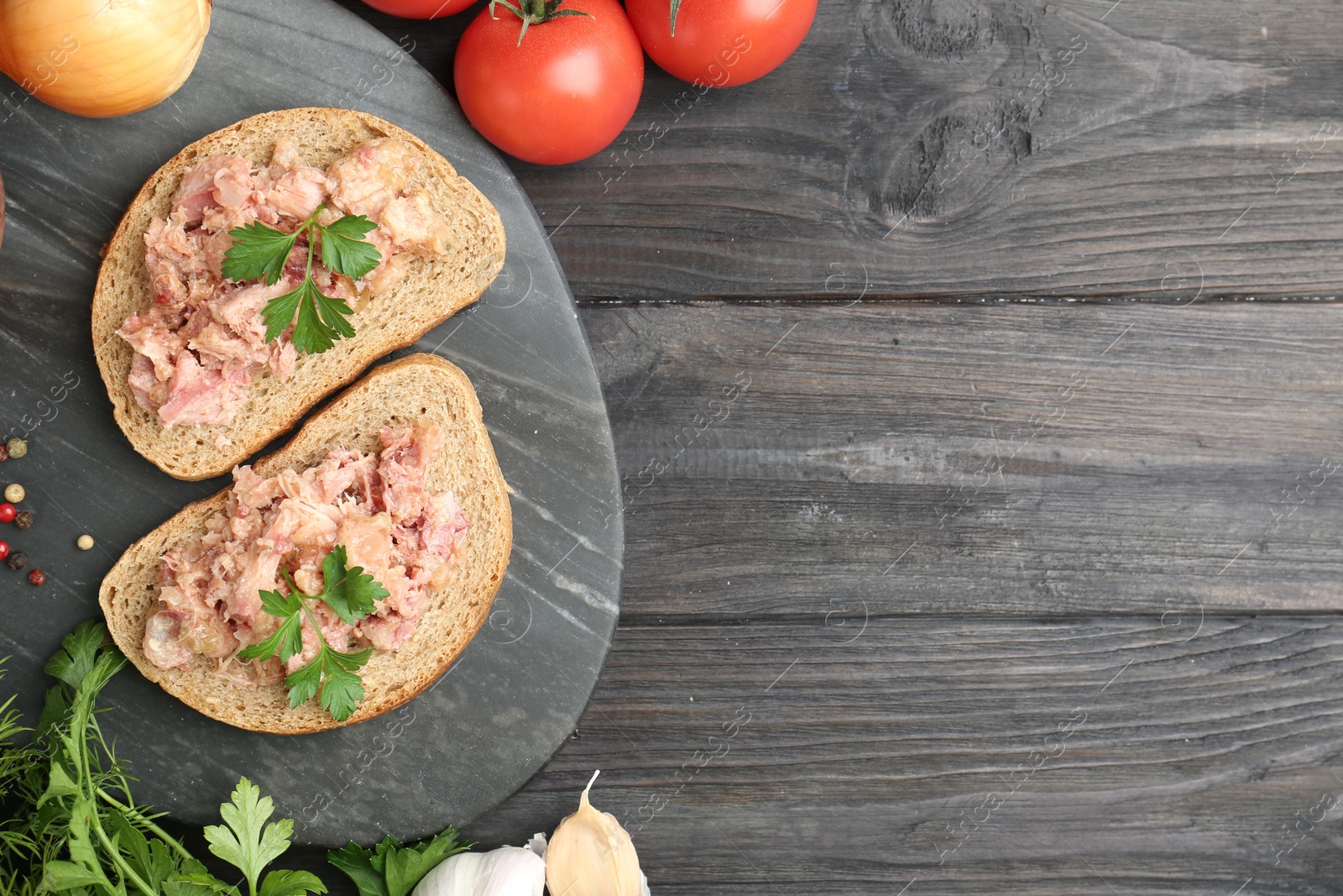 Photo of Sandwiches with canned meat served on wooden table, top view. Space for text