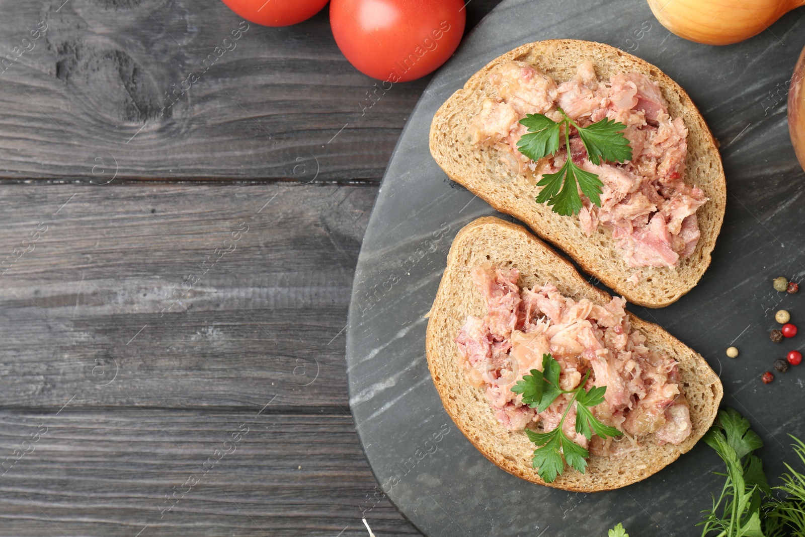 Photo of Sandwiches with canned meat served on wooden table, top view. Space for text