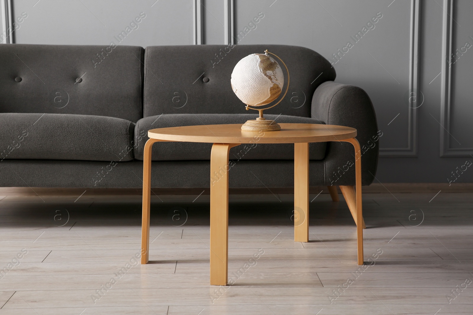 Photo of Stylish sofa and globe on coffee table in room