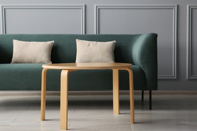 Photo of Stylish sofa with cushions and coffee table in room