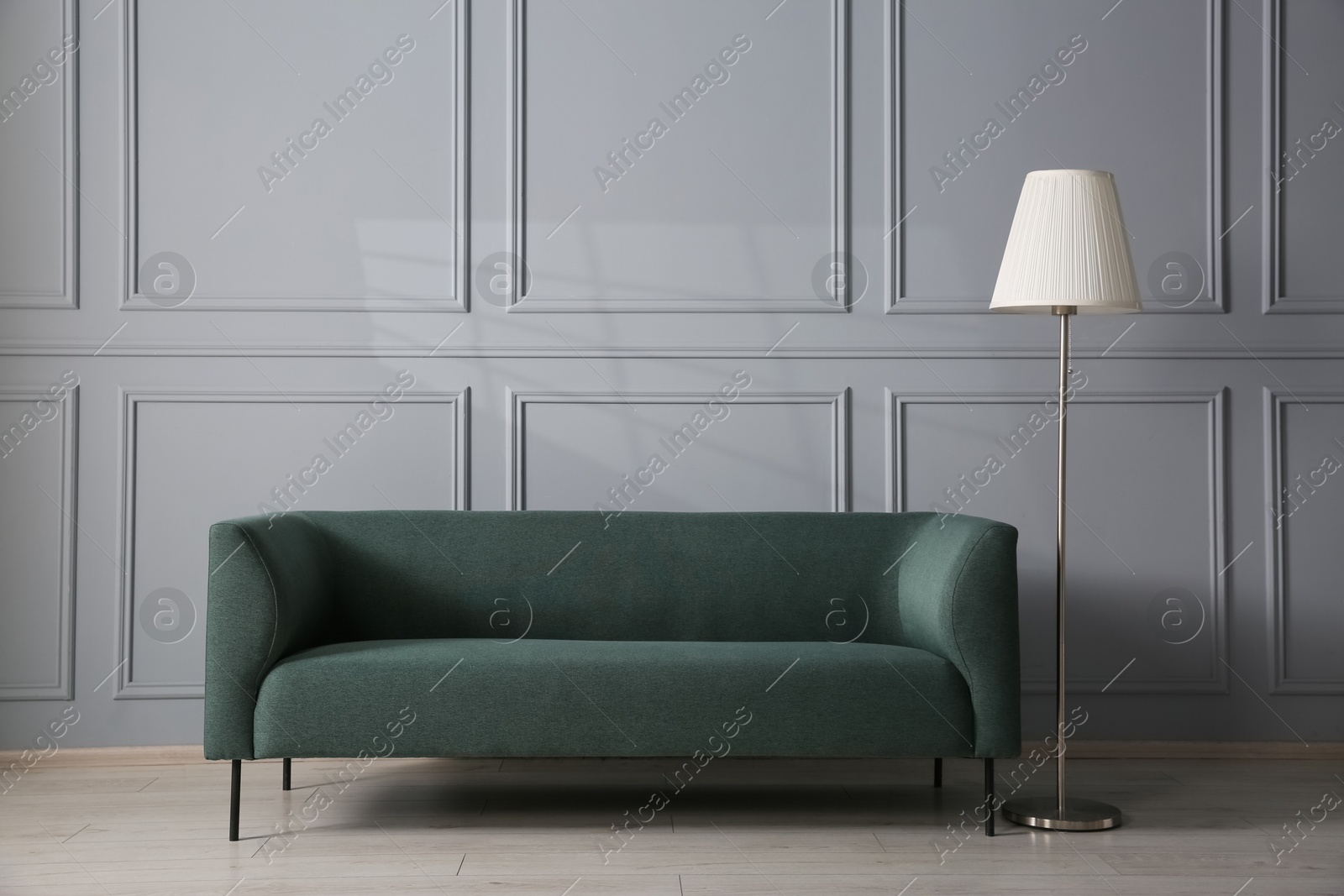 Photo of Comfortable sofa and lamp near grey wall in room