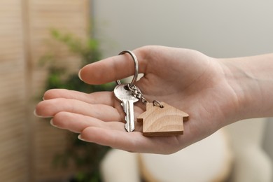 Photo of Woman holding key with house shaped keychain indoors, closeup