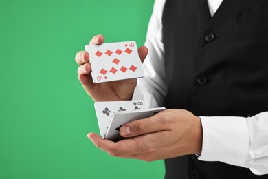 Photo of Professional croupier shuffling cards on green background, closeup. Space for text