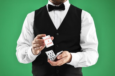 Photo of Professional croupier shuffling cards on green background, closeup