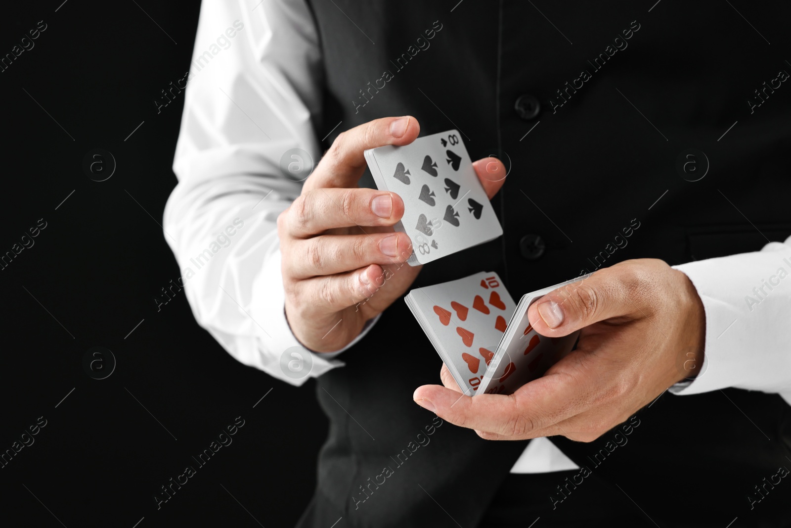 Photo of Professional croupier shuffling cards on black background, closeup