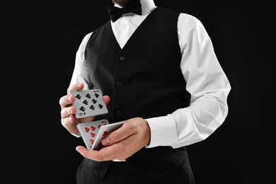 Photo of Professional croupier shuffling cards on black background, closeup