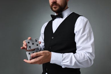 Professional croupier shuffling cards on grey background