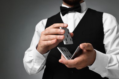 Professional croupier shuffling cards on grey background