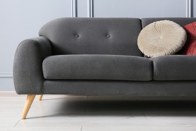 Photo of Stylish sofa with cushions near grey wall