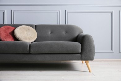 Photo of Stylish sofa with cushions near grey wall