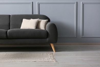 Photo of Stylish sofa with cushions near grey wall, space for text