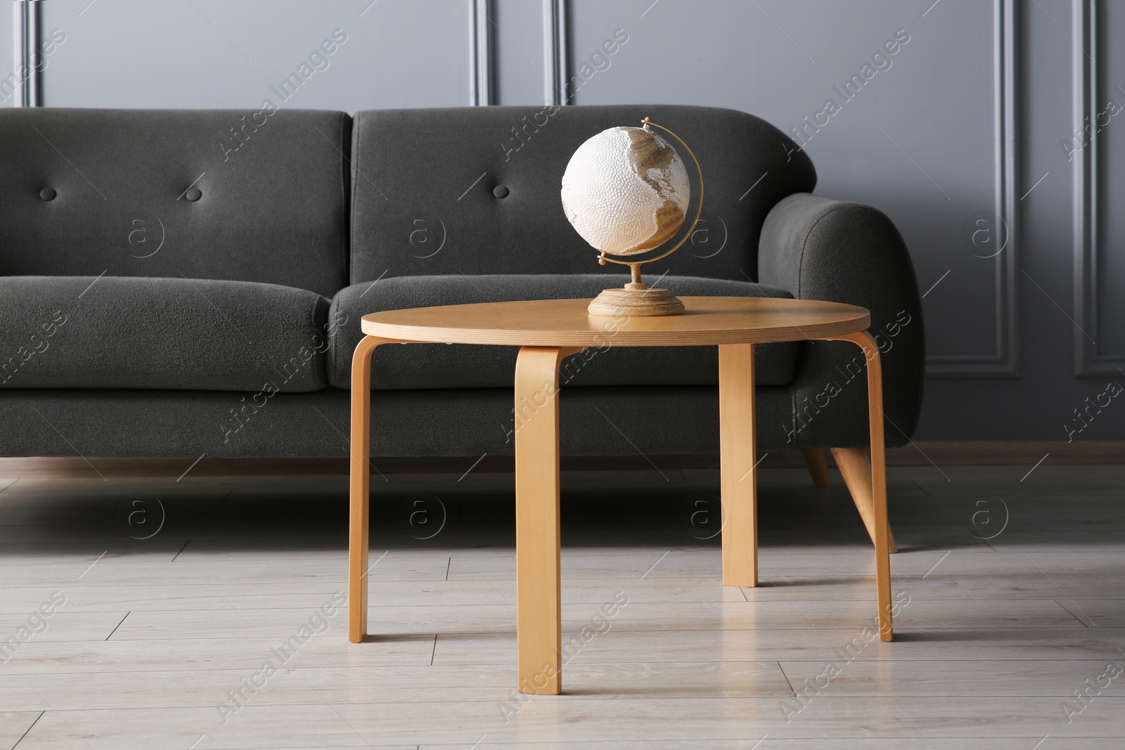 Photo of Stylish sofa and globe on coffee table in room