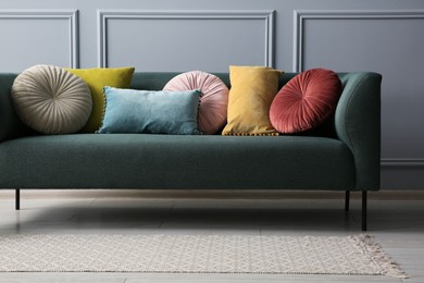 Photo of Stylish sofa with different cushions near grey wall