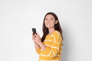 Photo of Smiling woman with smartphone on white background