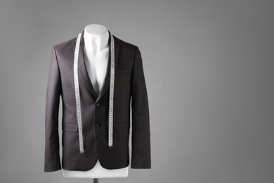 Photo of Male mannequin with brown jacket and measuring tape on grey background, space for text