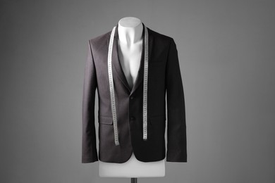 Photo of Male mannequin with brown jacket and measuring tape on grey background