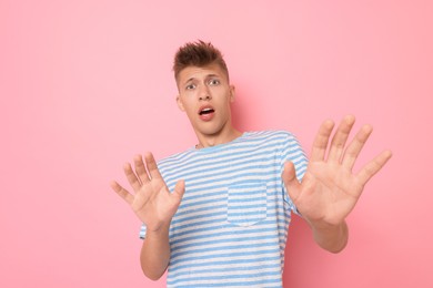 Portrait of scared young man on pink background