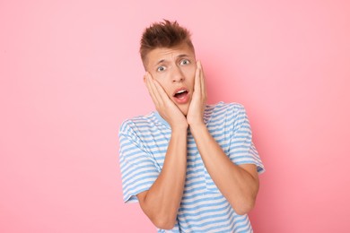 Portrait of scared young man on pink background