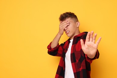 Photo of Portrait of scared young man on orange background, space for text