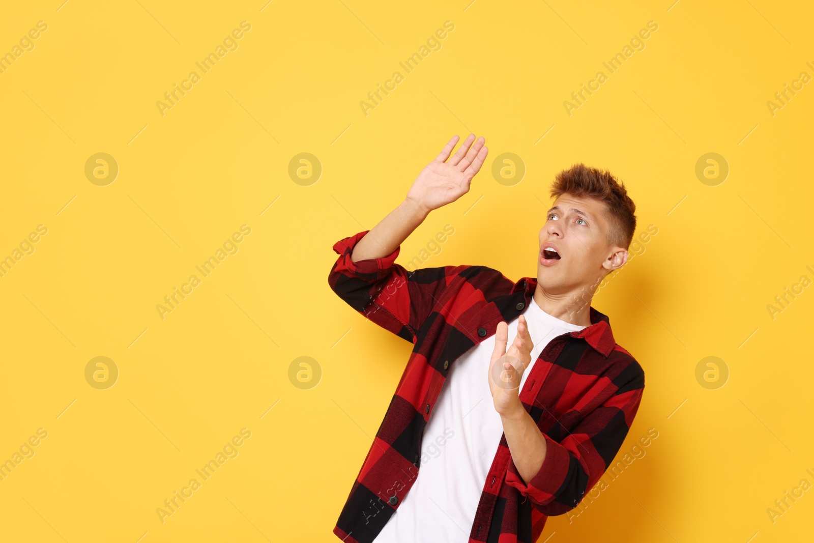 Photo of Portrait of scared young man on orange background, space for text