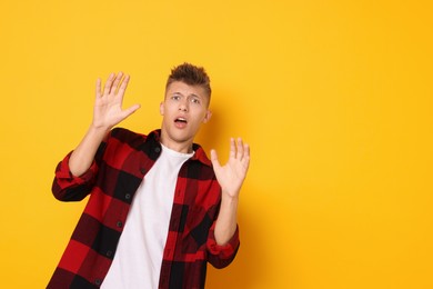 Photo of Portrait of scared young man on orange background, space for text