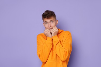 Photo of Portrait of scared young man on violet background, space for text