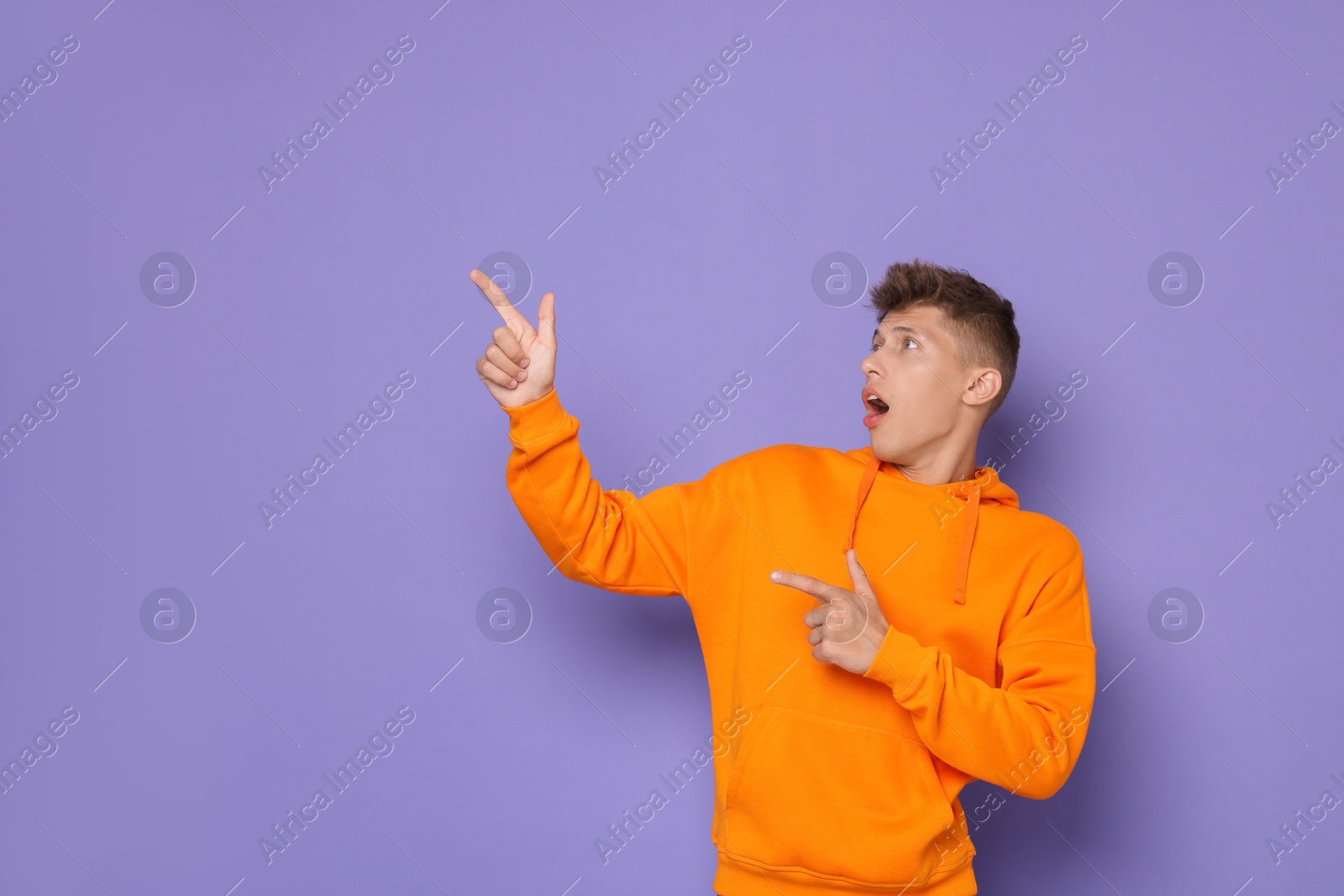 Photo of Portrait of scared young man on violet background, space for text