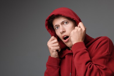 Portrait of scared young man on gray background, space for text