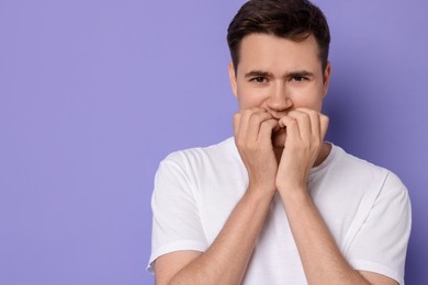 Photo of Portrait of scared young man on violet background, space for text