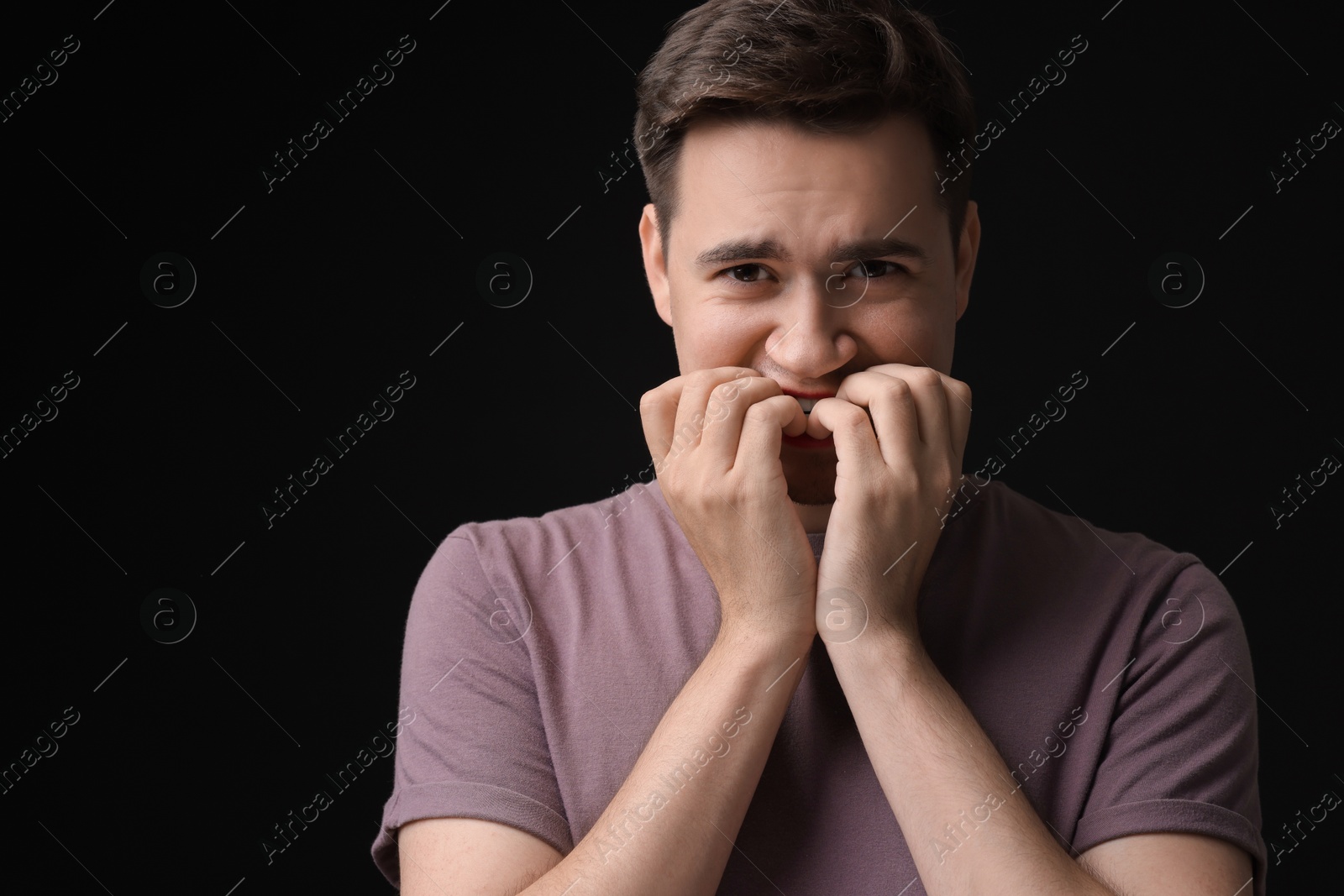 Photo of Portrait of scared young man on black background, space for text