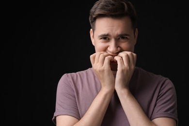 Photo of Portrait of scared young man on black background, space for text