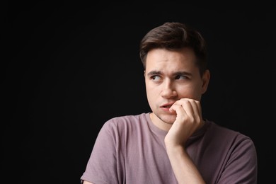 Photo of Portrait of scared young man on black background, space for text