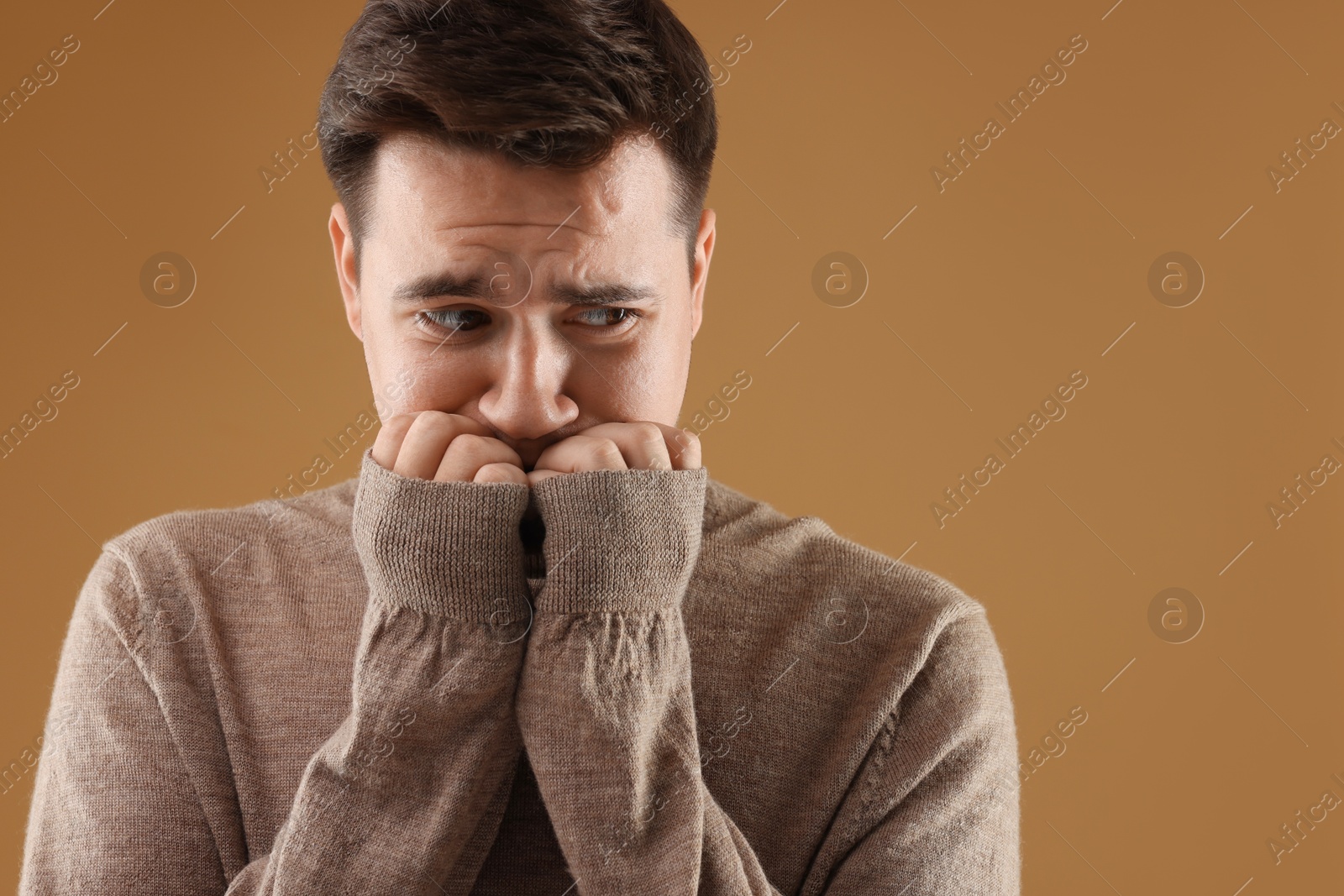 Photo of Portrait of scared young man on brown background, space for text