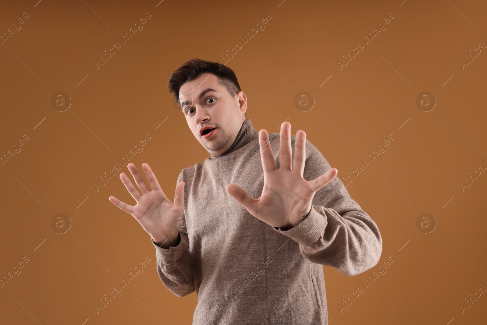 Photo of Portrait of scared young man on brown background