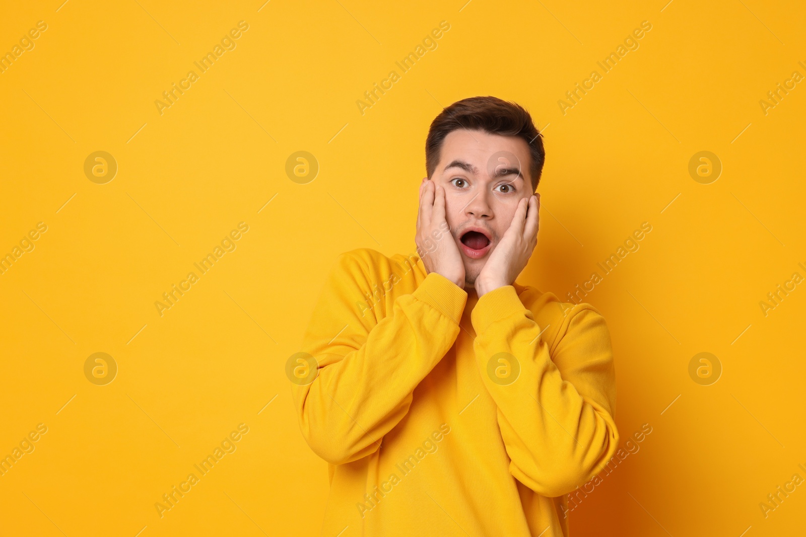 Photo of Portrait of scared young man on orange background, space for text