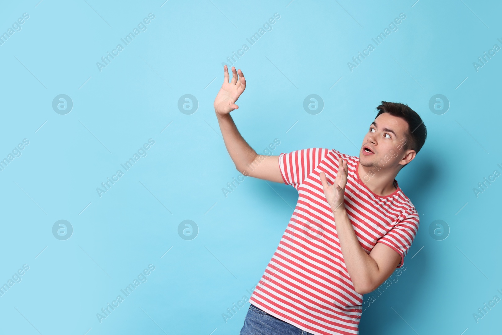 Photo of Portrait of scared young man on light blue background, space for text