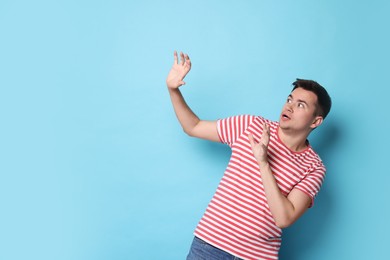 Photo of Portrait of scared young man on light blue background, space for text