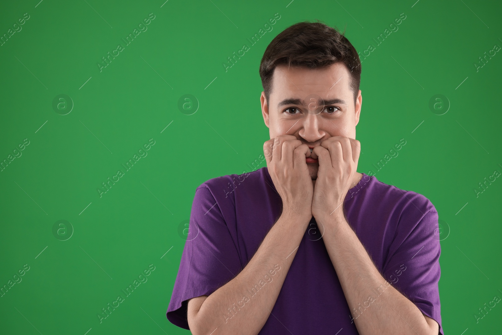 Photo of Portrait of scared young man on green background, space for text