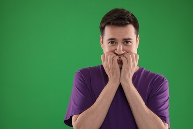 Photo of Portrait of scared young man on green background, space for text