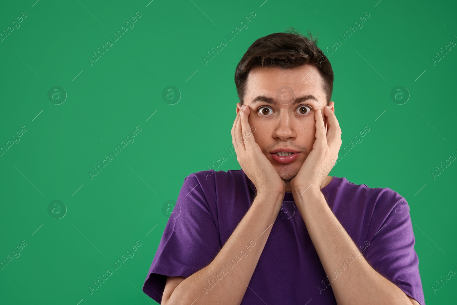 Photo of Portrait of scared young man on green background, space for text