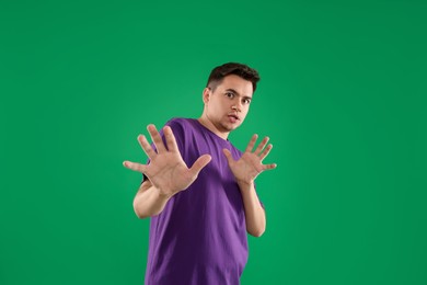 Portrait of scared young man on green background