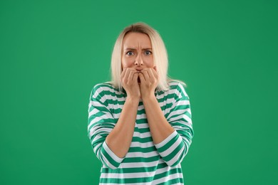 Portrait of scared woman on green background, space for text