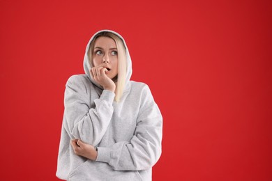 Photo of Portrait of scared woman on red background, space for text