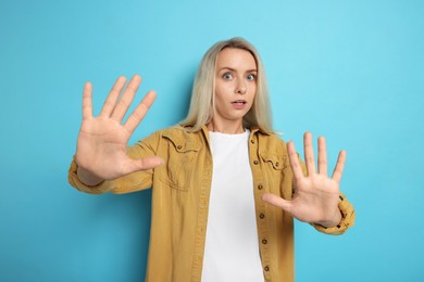 Portrait of scared woman on light blue background