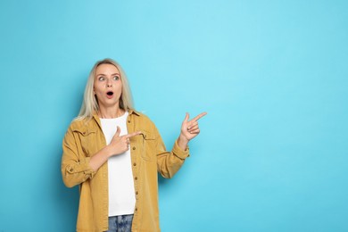 Portrait of scared woman on light blue background, space for text