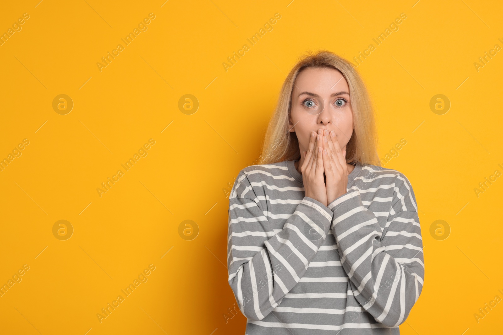 Photo of Portrait of scared woman on orange background, space for text