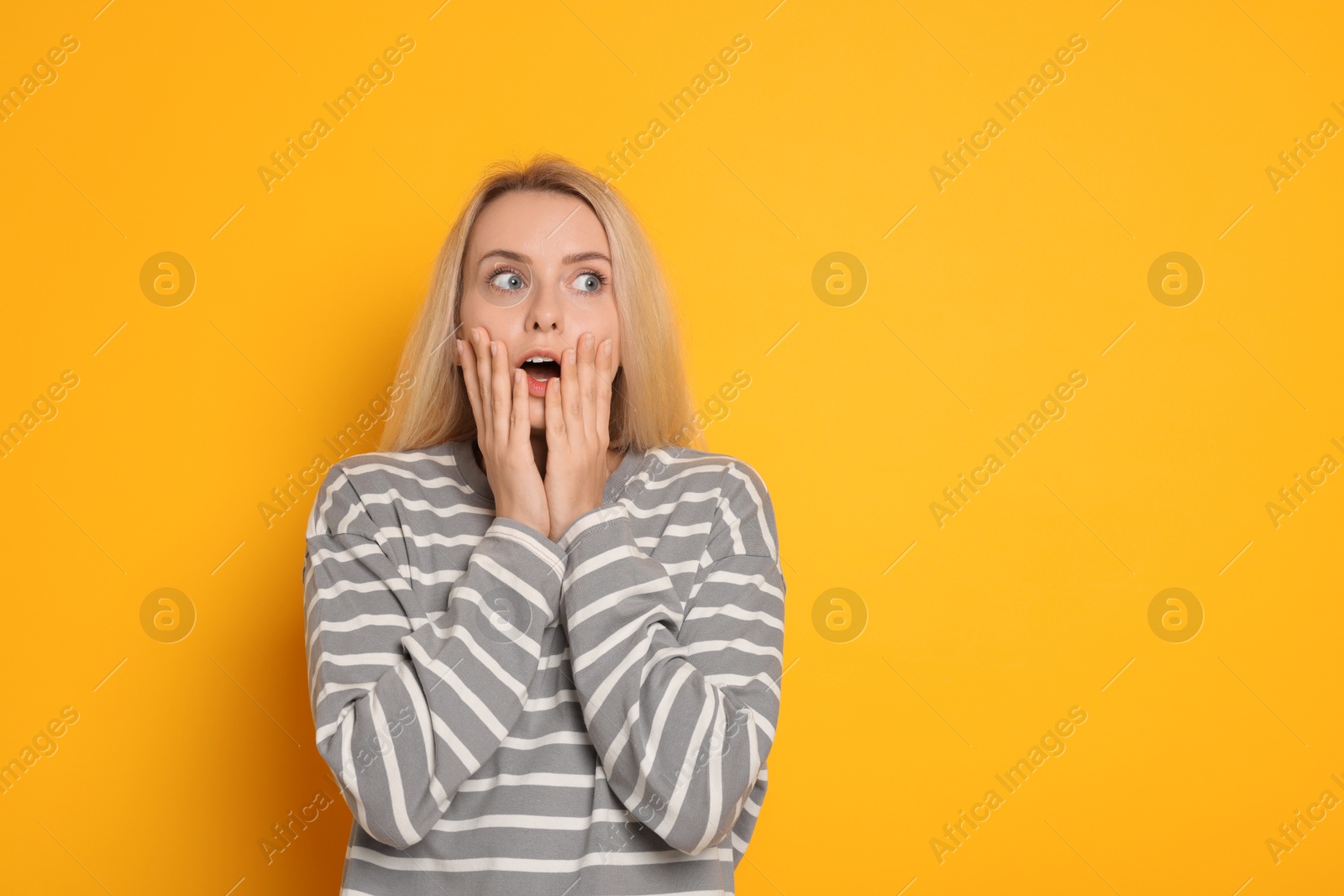 Photo of Portrait of scared woman on orange background, space for text