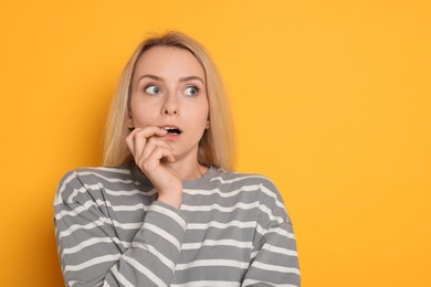 Portrait of scared woman on orange background, space for text