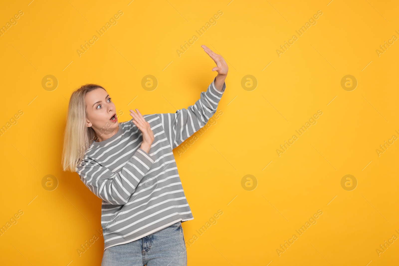 Photo of Portrait of scared woman on orange background, space for text