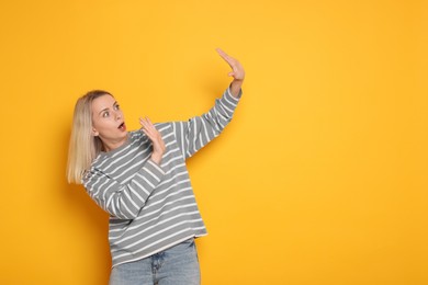 Portrait of scared woman on orange background, space for text